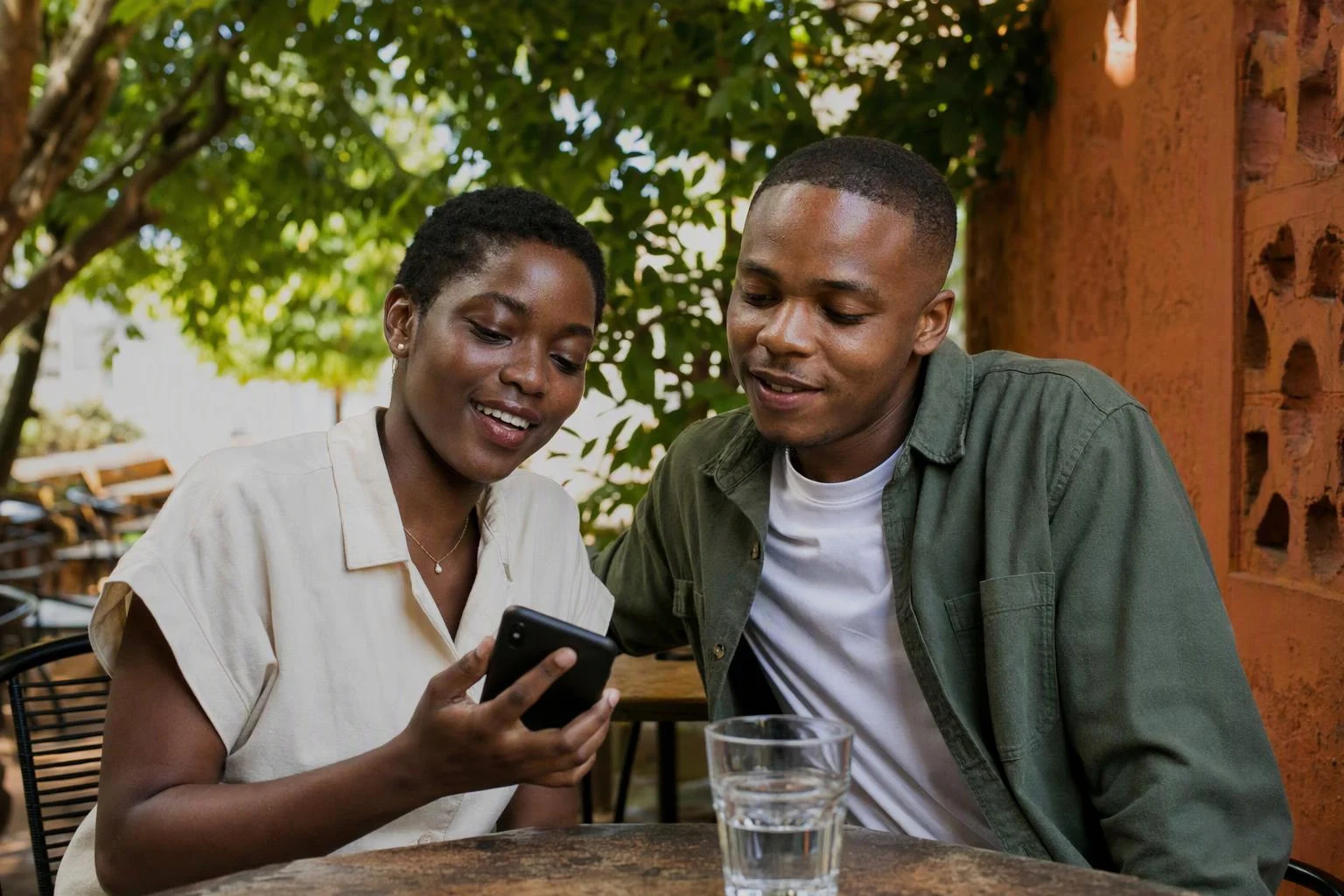 Two friends sharing a phone at an outdoor café